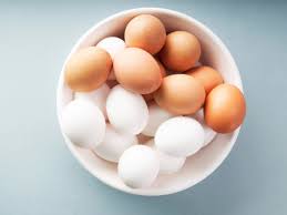 a white bowl containing both brown and white eggs