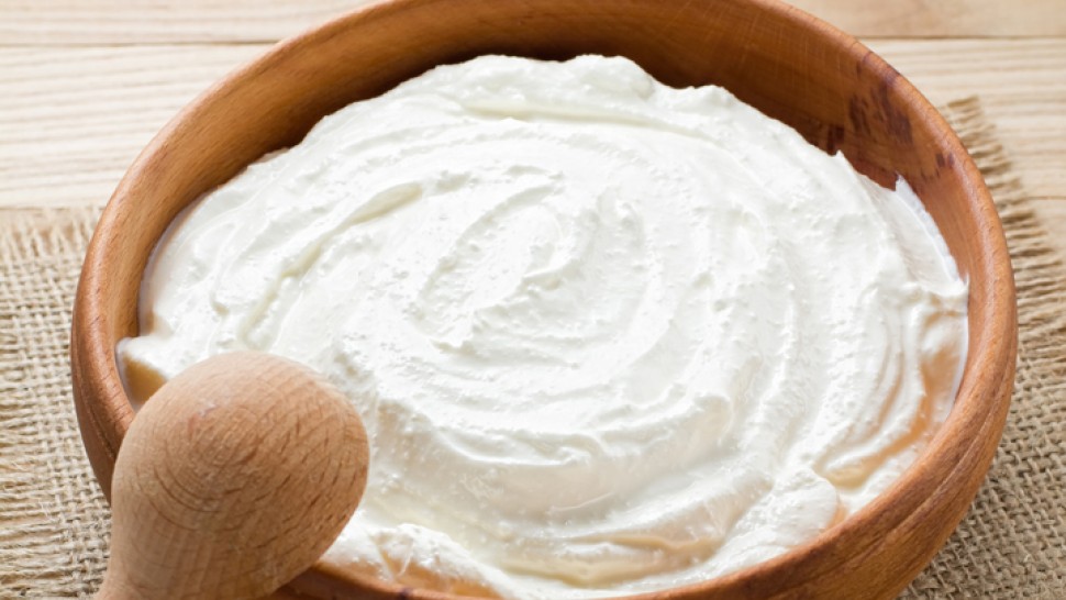 wooden bowl containing greek yogurt with a wooden spoon