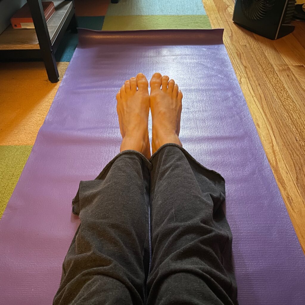 Pic of legs and feet on a purple yoga mat on the floor