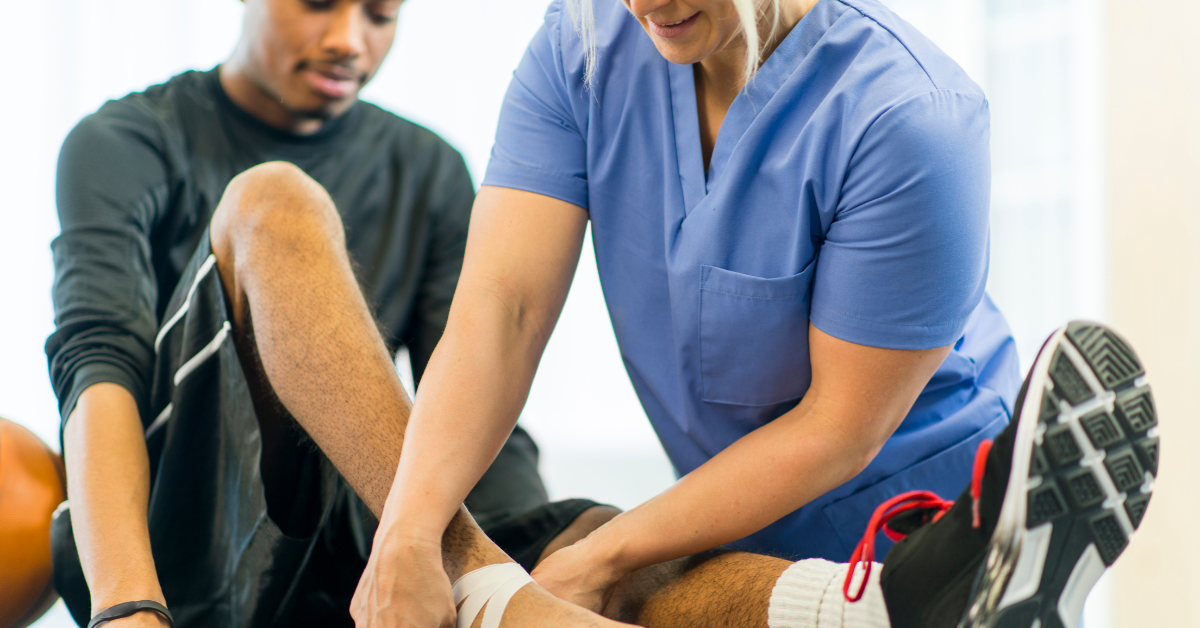 Physical therapist taping up an athletes ankle on top of a PT table