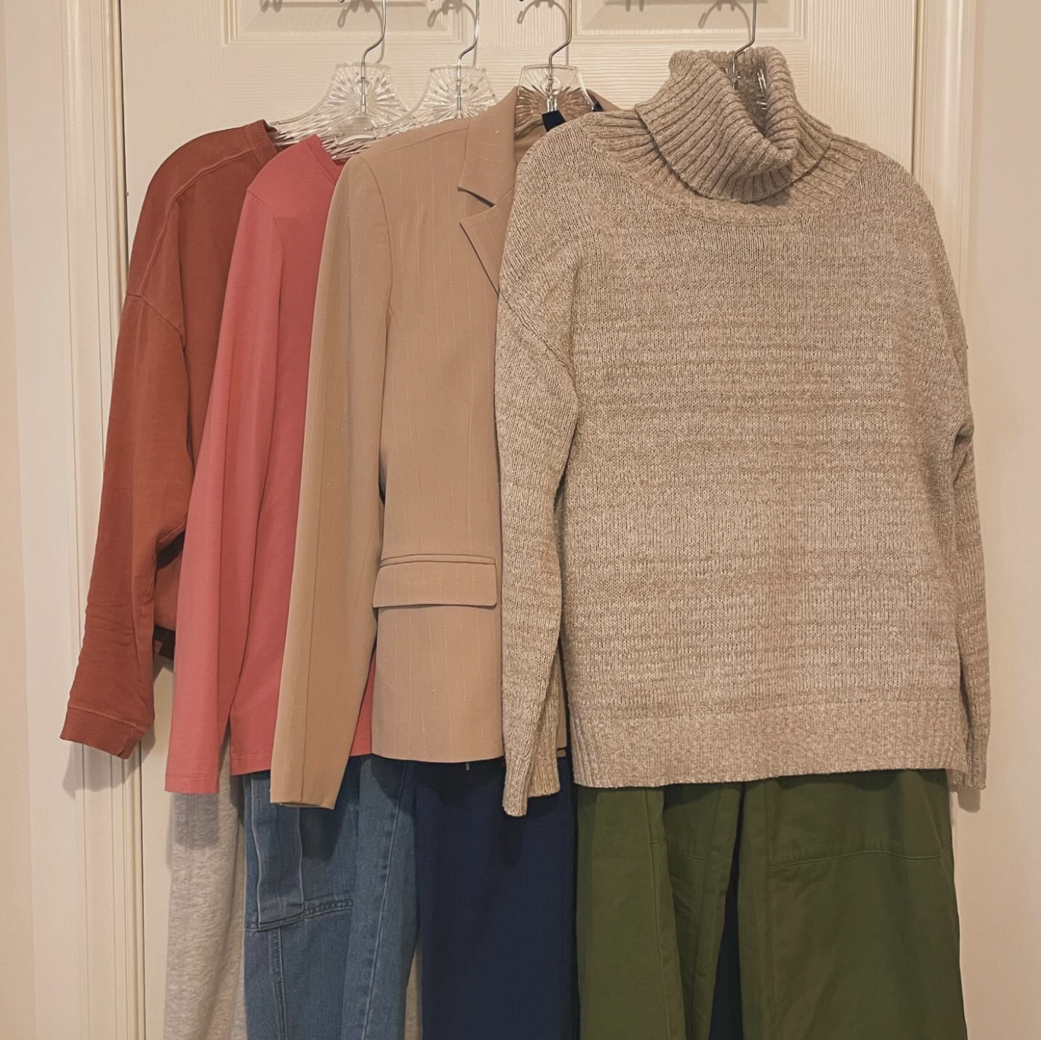 Various outfits hang on the back of a door