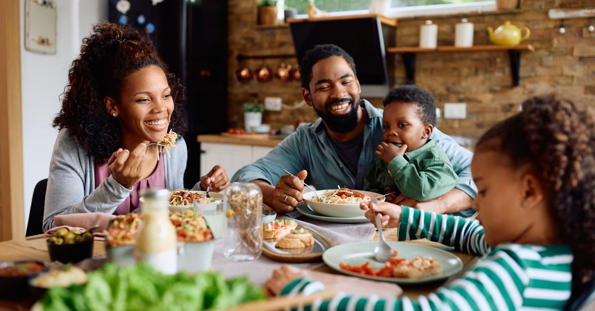 Family around a dinner table, eating and smiling